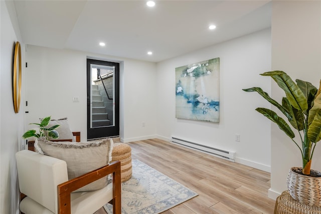 living area with light wood-type flooring and baseboard heating