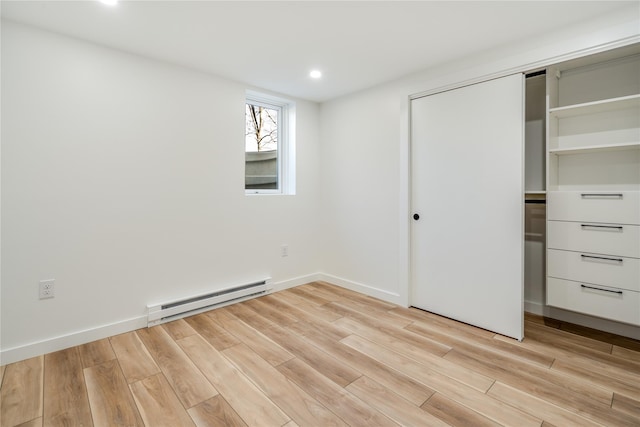 unfurnished bedroom with a closet, light hardwood / wood-style floors, and baseboard heating