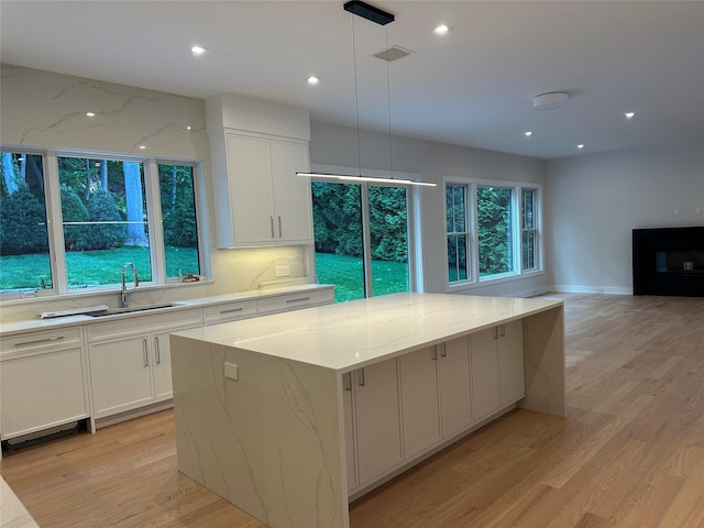 239 Rock Creek Ln, Scarsdale, NY 10583 - kitchen featuring a sink, light wood-type flooring, white cabinets, light stone countertops, and recessed lighting