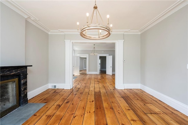 unfurnished living room featuring a high end fireplace, ornamental molding, and light wood-type flooring