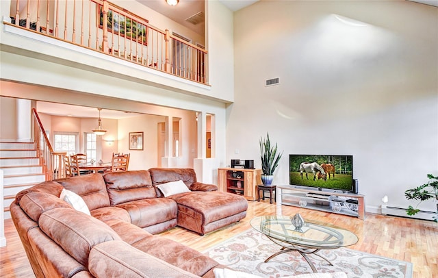 living room with a high ceiling, hardwood / wood-style flooring, and baseboard heating