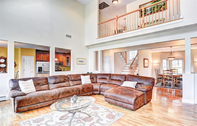 living room with a towering ceiling and light hardwood / wood-style flooring