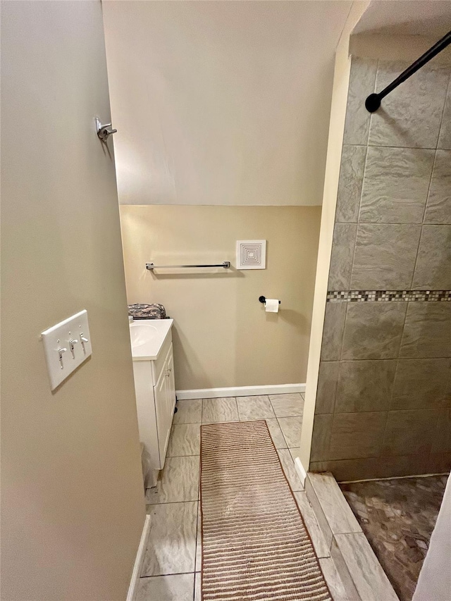 bathroom with a tile shower and vanity