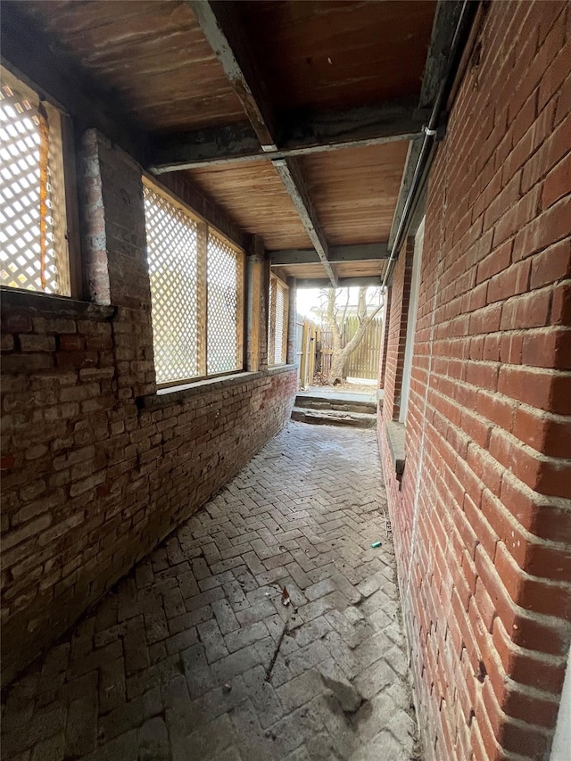 interior space featuring wood ceiling and brick wall