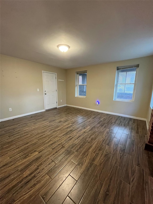 empty room with dark hardwood / wood-style floors and a healthy amount of sunlight