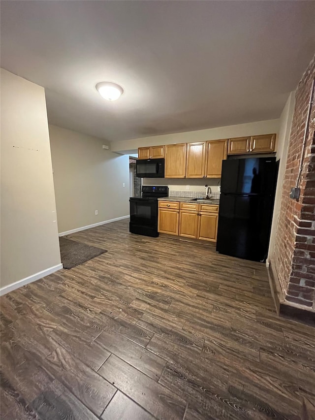 kitchen with black appliances, dark hardwood / wood-style floors, sink, and brick wall