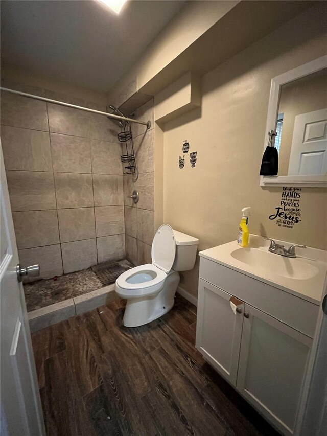 bathroom featuring tiled shower, vanity, hardwood / wood-style flooring, and toilet