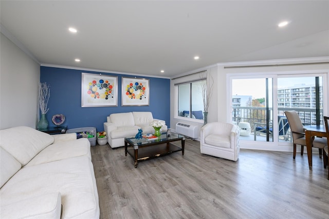 living room featuring a wall mounted AC, ornamental molding, and light wood-type flooring