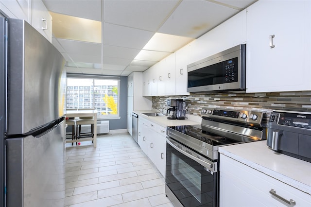 kitchen with white cabinetry, sink, tasteful backsplash, a paneled ceiling, and appliances with stainless steel finishes