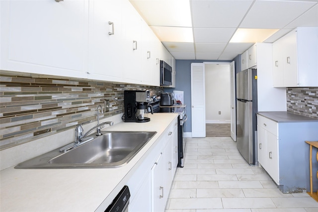 kitchen with a drop ceiling, sink, decorative backsplash, appliances with stainless steel finishes, and white cabinetry