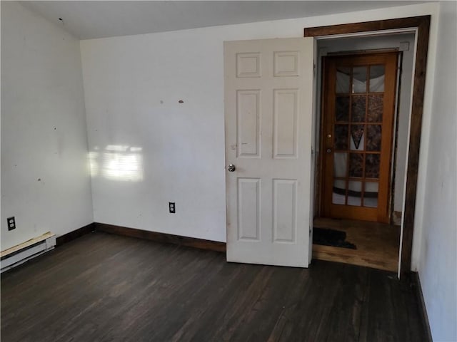 unfurnished room with dark hardwood / wood-style flooring and a baseboard heating unit