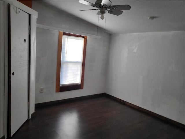 empty room featuring dark hardwood / wood-style floors, ceiling fan, and vaulted ceiling