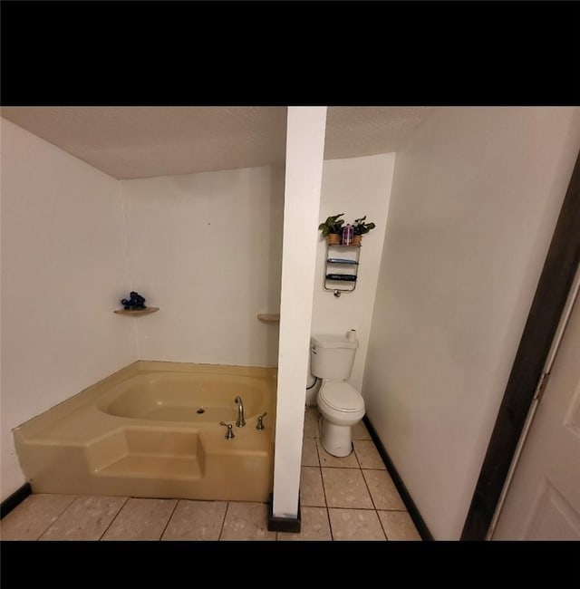 bathroom featuring toilet, a washtub, and tile patterned flooring