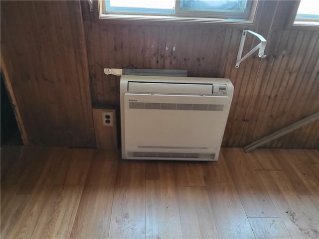 details with hardwood / wood-style flooring, heating unit, and wooden walls