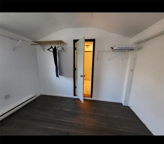 walk in closet with dark hardwood / wood-style flooring, vaulted ceiling, and a baseboard heating unit