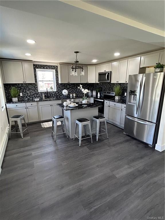 kitchen featuring a center island, stainless steel appliances, a kitchen breakfast bar, dark hardwood / wood-style floors, and pendant lighting