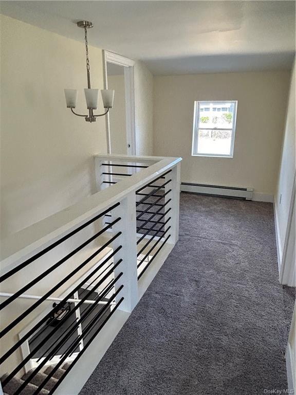 corridor with dark carpet, baseboard heating, and a notable chandelier