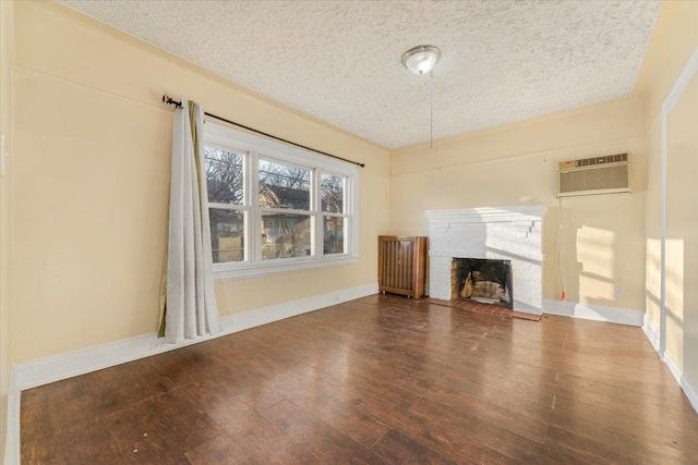 unfurnished living room featuring an AC wall unit, a fireplace, a textured ceiling, and hardwood / wood-style flooring