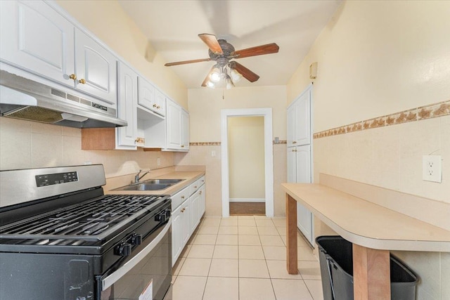 kitchen with stainless steel gas range oven, white cabinets, sink, ceiling fan, and light tile patterned floors