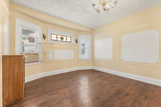 unfurnished room with dark hardwood / wood-style floors, cooling unit, a textured ceiling, and a chandelier