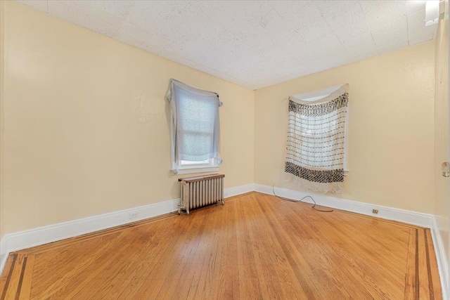 spare room with wood-type flooring, a textured ceiling, and radiator