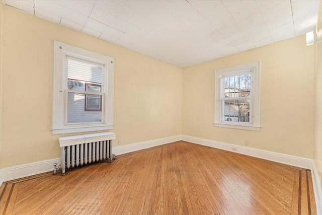 empty room featuring radiator heating unit and light hardwood / wood-style floors