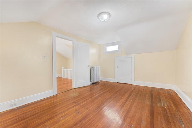 bonus room with hardwood / wood-style floors, lofted ceiling, and radiator heating unit