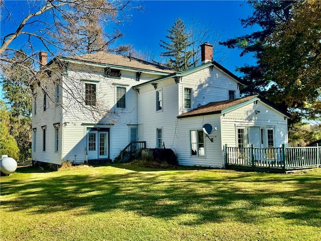 rear view of house featuring a deck and a lawn