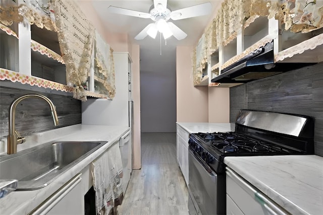 kitchen featuring white cabinetry, sink, ceiling fan, stainless steel gas range, and light wood-type flooring