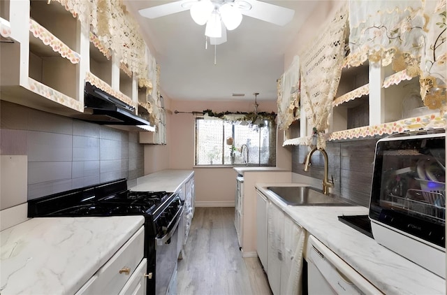 kitchen featuring decorative backsplash, light wood-type flooring, gas stove, sink, and white cabinetry