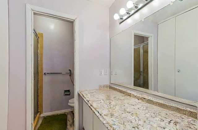 bathroom featuring toilet, an enclosed shower, and vanity