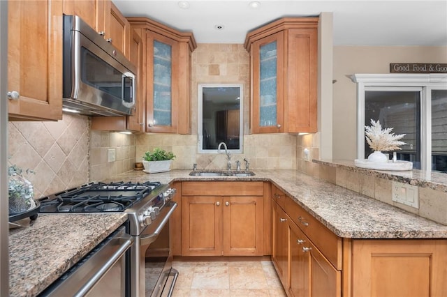 kitchen with light stone counters, sink, stainless steel appliances, and tasteful backsplash