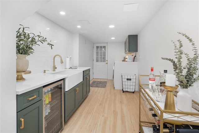 kitchen with decorative backsplash, sink, beverage cooler, and light wood-type flooring