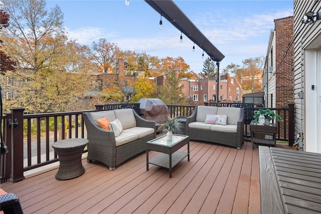 wooden terrace with area for grilling and an outdoor living space