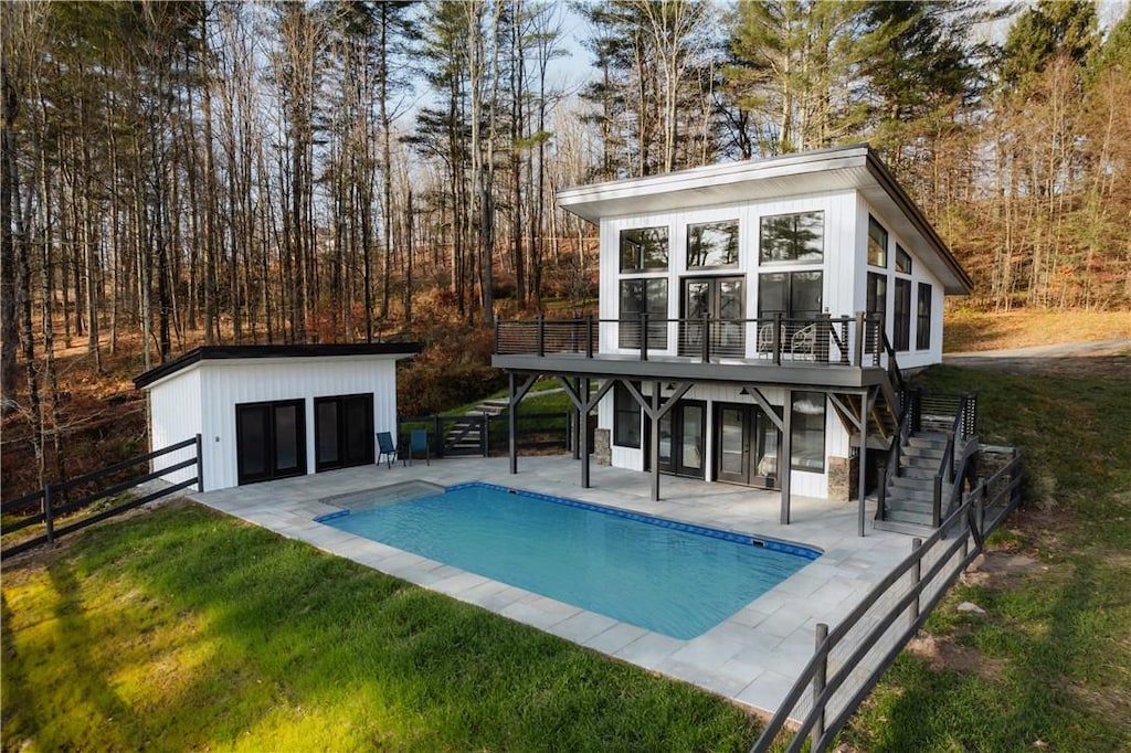 back of house featuring a sunroom, a yard, an outdoor structure, a pool side deck, and a patio