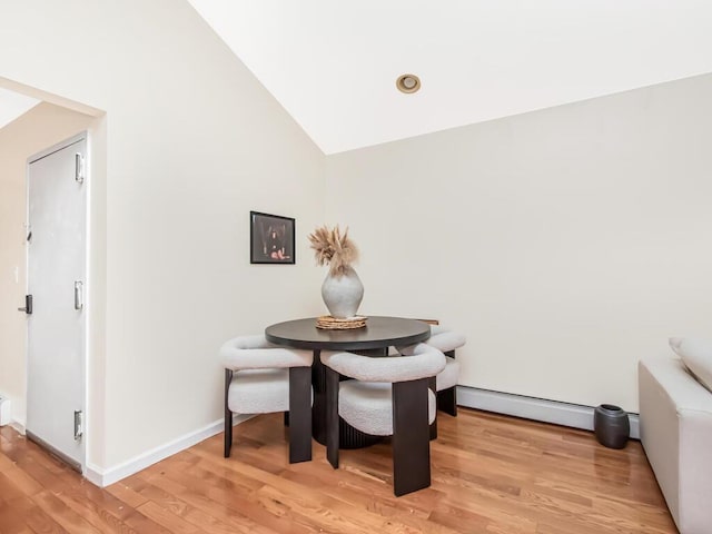 dining room with light wood-type flooring, baseboard heating, and high vaulted ceiling