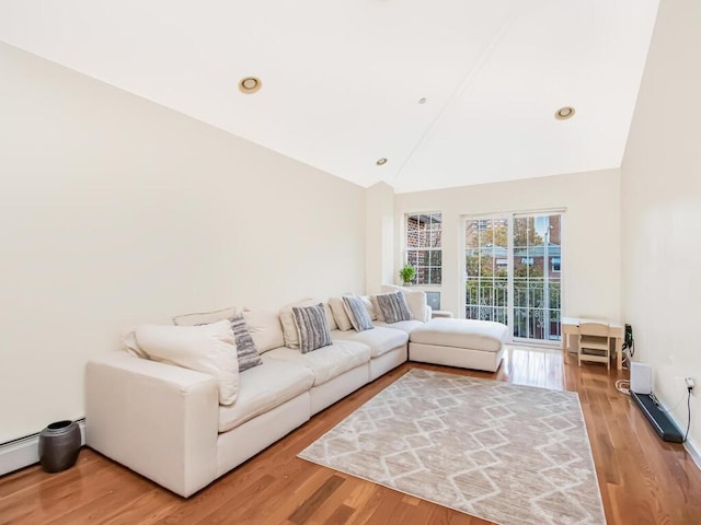 living room with wood-type flooring, high vaulted ceiling, and a baseboard heating unit