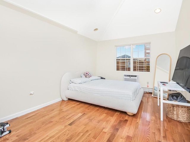 bedroom featuring hardwood / wood-style floors, a baseboard radiator, vaulted ceiling, and a wall mounted AC