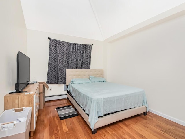 bedroom featuring light wood-type flooring, lofted ceiling, and a baseboard heating unit