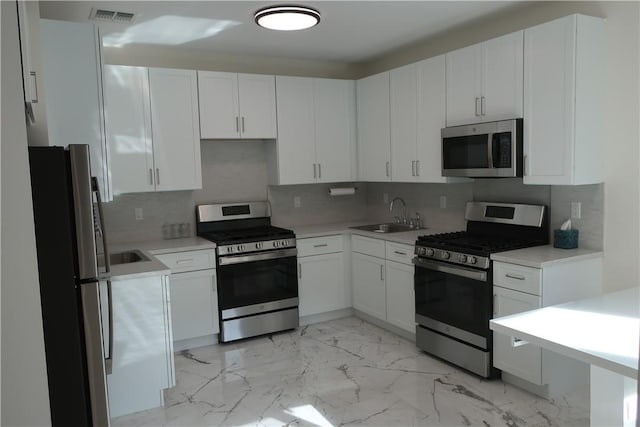 kitchen featuring decorative backsplash, sink, white cabinets, and stainless steel appliances