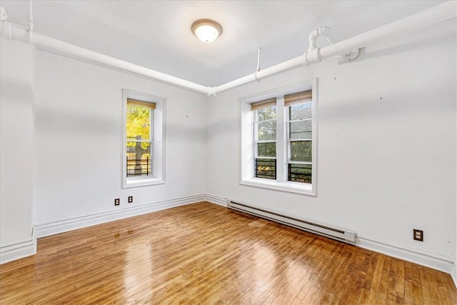 spare room featuring hardwood / wood-style floors and a baseboard heating unit