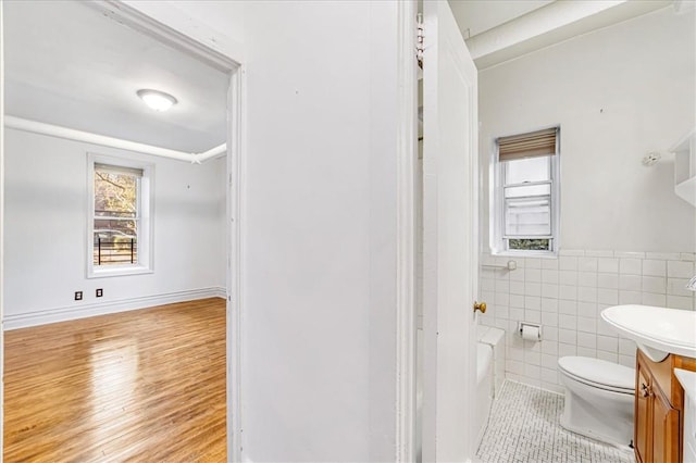 bathroom with vanity, hardwood / wood-style flooring, tile walls, toilet, and a bathing tub