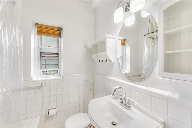 bathroom with a shower with shower curtain, toilet, sink, and tile walls