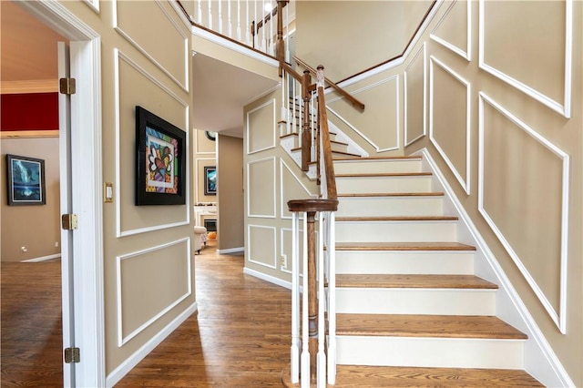 staircase featuring wood-type flooring and crown molding