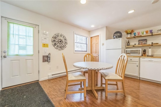 dining space featuring a healthy amount of sunlight, light hardwood / wood-style floors, and a baseboard radiator