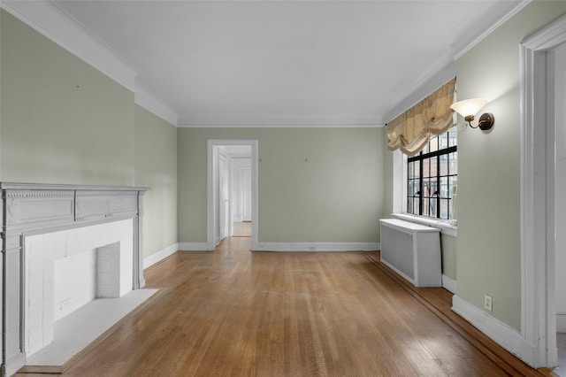 unfurnished living room featuring a brick fireplace, radiator heating unit, ornamental molding, and light hardwood / wood-style flooring