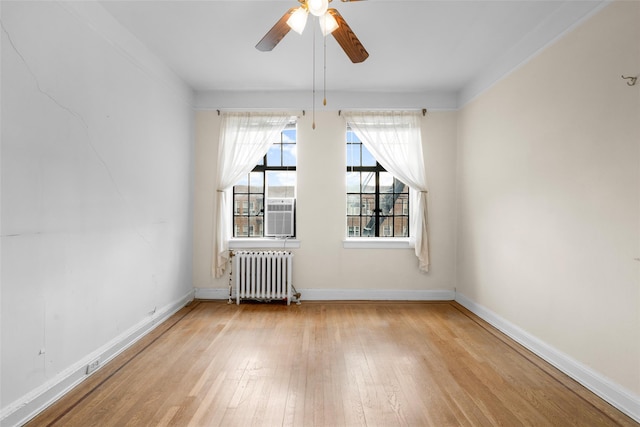 empty room featuring ceiling fan, radiator heating unit, and light hardwood / wood-style floors