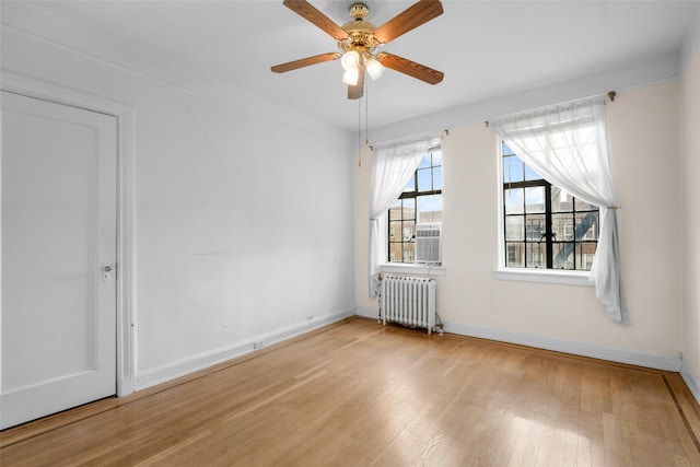 spare room with ceiling fan, radiator heating unit, and light hardwood / wood-style flooring