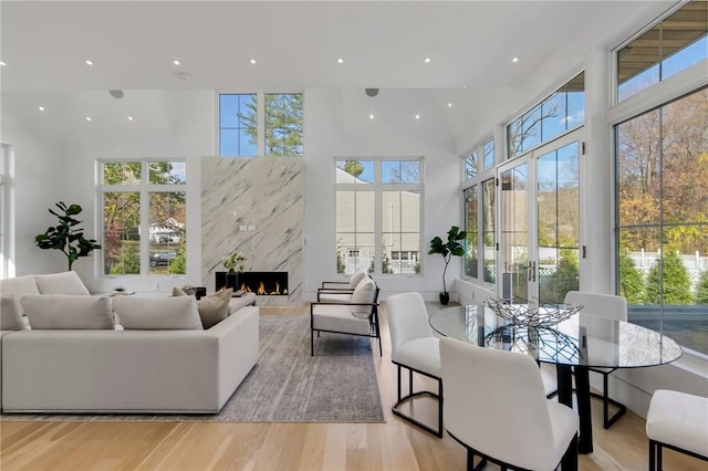 living room with a high end fireplace, a high ceiling, and light hardwood / wood-style floors