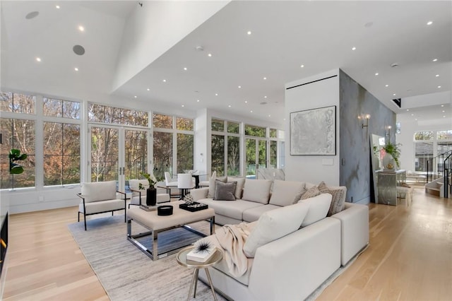 living room featuring a wealth of natural light, french doors, high vaulted ceiling, and light wood-type flooring